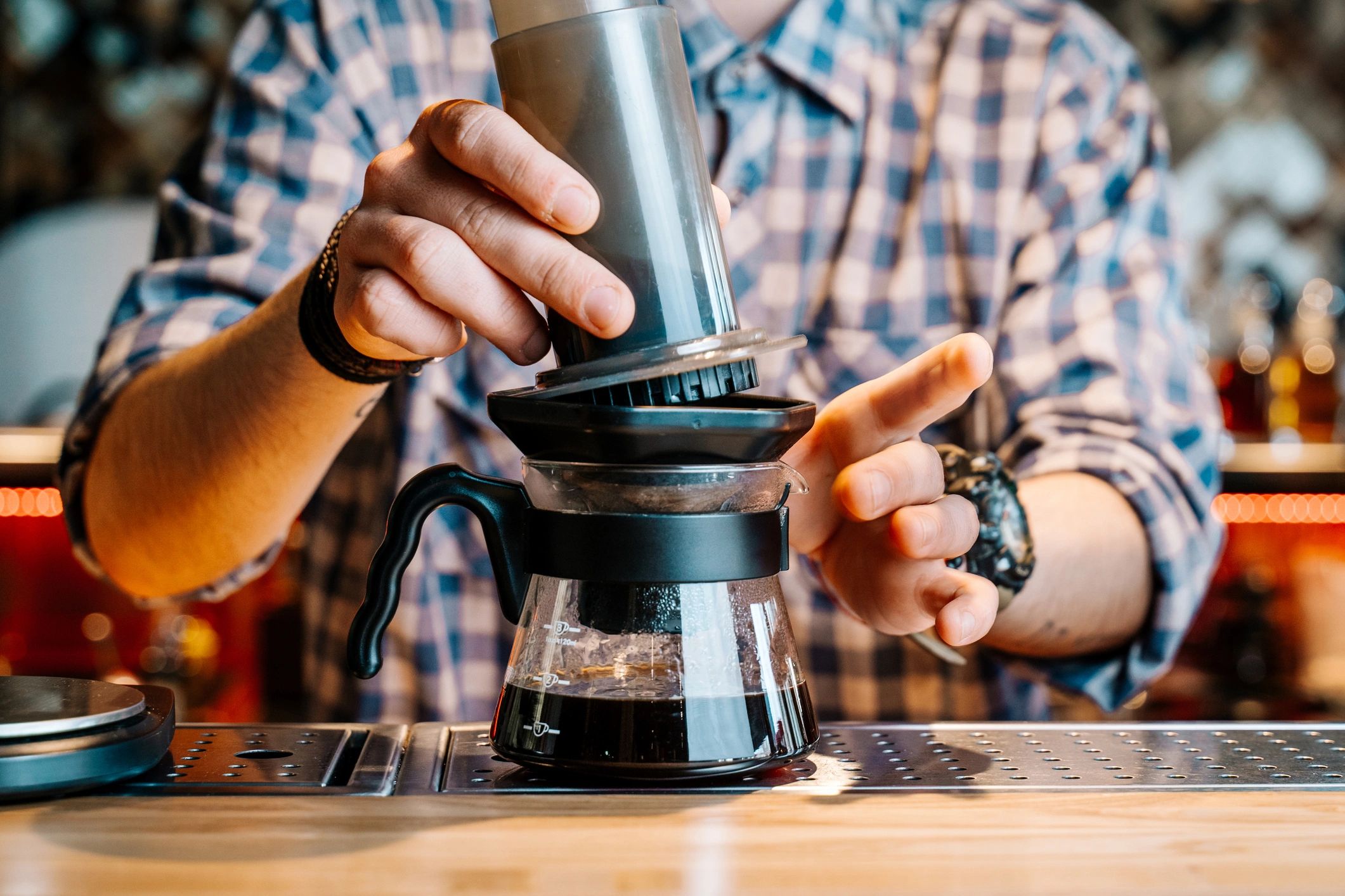 Barista preparing coffee with an AeroPress at a counter