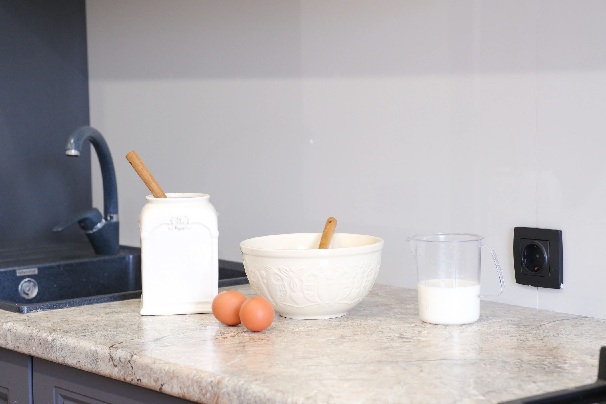 Kitchen table with milk, eggs, sugar and mixing bowl