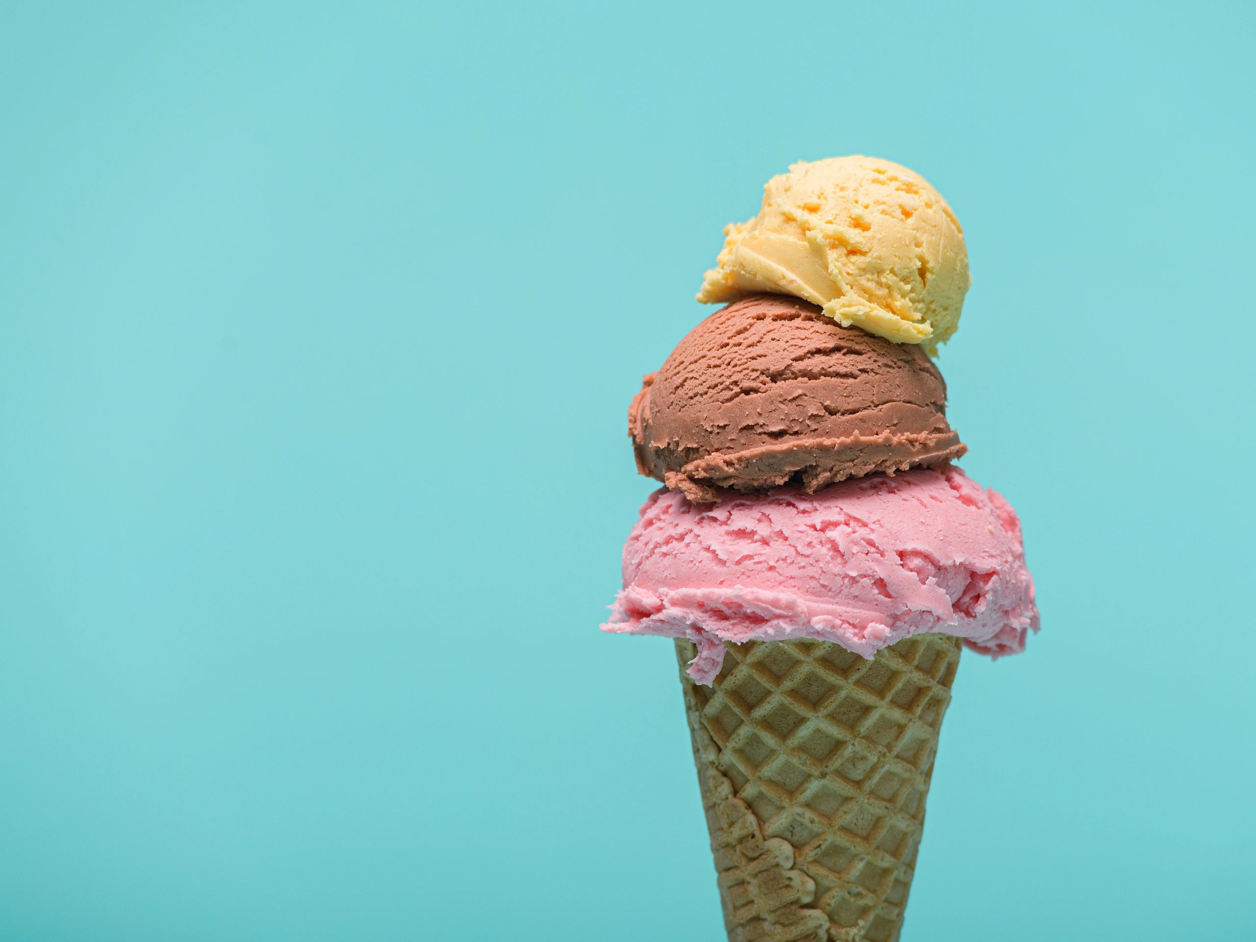 Triple scoop ice cream cone on blue background