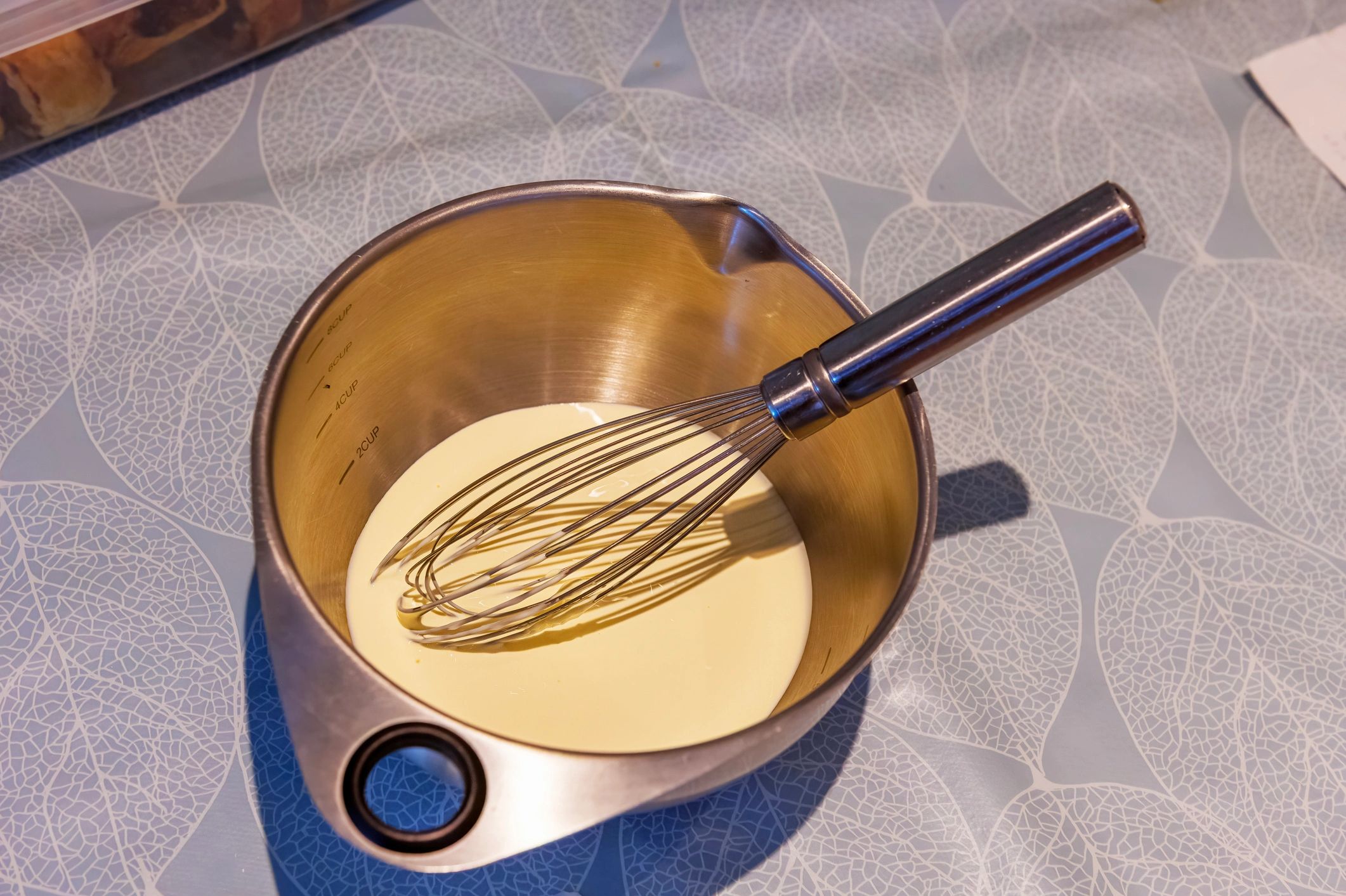 Cream in a metal mixing bowl with a whisk