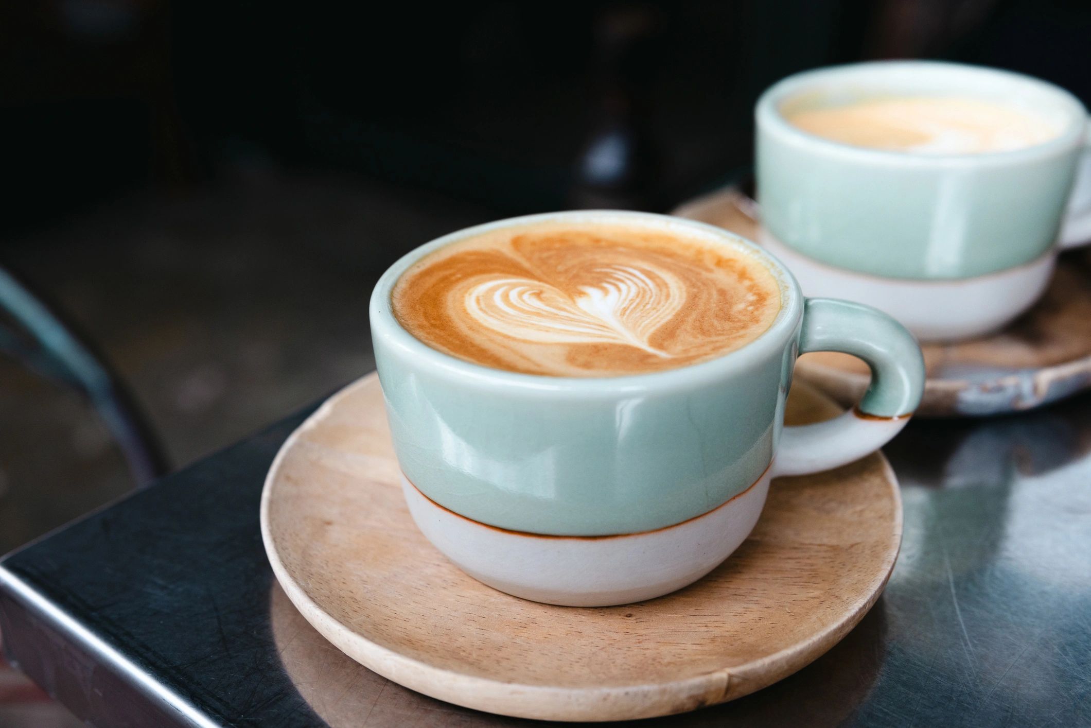 Green mug with latte art on a table